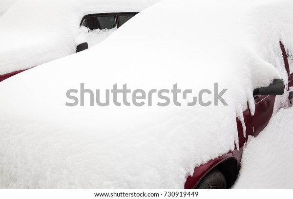 Passenger cars in the snowdrift (snow bank) on\
the parking lot. Car covered with snow after the snowstorm in\
winter. Close-up.