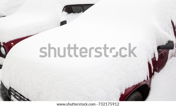 Passenger cars in the snowdrift (snow bank) on\
the parking lot. Car covered with snow after the snowstorm in\
winter. Close-up.