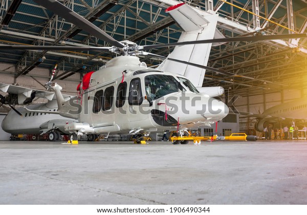 Passenger helicopter and airplanes in the\
hangar. Rotorcraft and aircrafts under maintenance. Checking\
mechanical systems for flight\
operations
