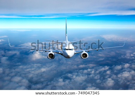 Passenger jet plane in the sky. Airplane flies high through the clouds. Aircraft front view.