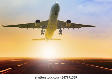 Passenger Jet Plane Take Off From Airport Runway With Beautiful Light Of Sun Rising Behind