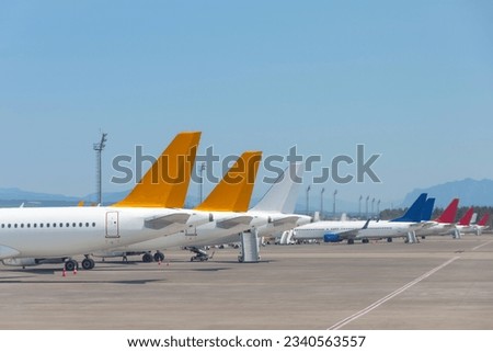 Passenger jets lined up in parking lots, tails view