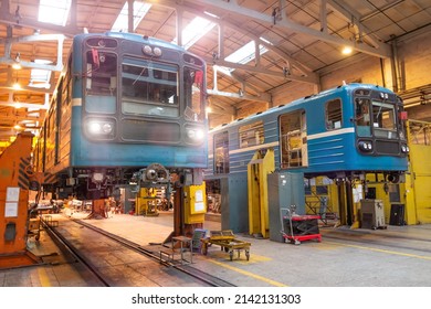 Passenger locomotives of the underground metro raised on jacks with headlights on in the depot, maintenance and replacement of engines and wheelsets, bogies