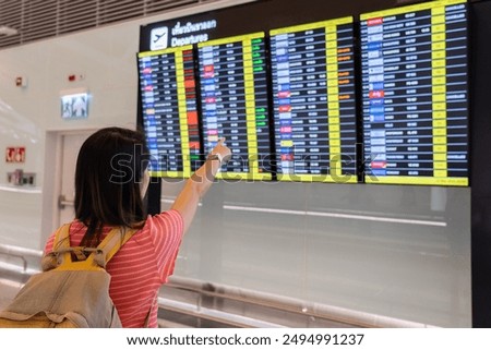 Passenger Looking at Flight Schedule in Terminal Area of Airport