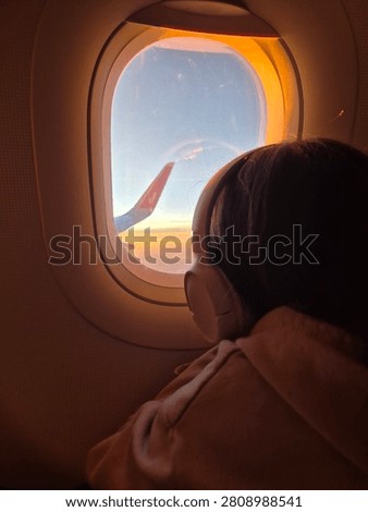 Passenger looking through airplane window at sunset