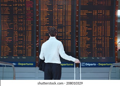 passenger looking at timetable board at the airport - Shutterstock ID 208010329