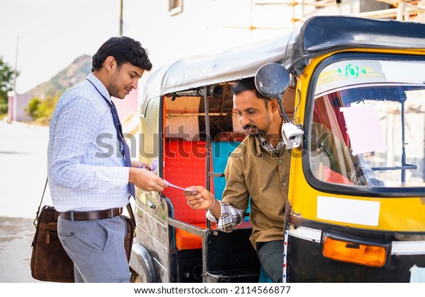 Passenger paying\
money to auto rickshaw driver after ride - concept of earnings,\
transportation and\
commutation