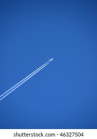 passenger plane flies across a blue sky leaving vapour trails