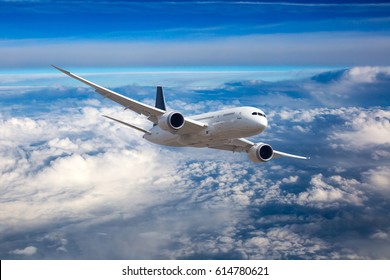 Пассажирский самолет в полете. Самолет летит высоко в голубом небе над облаками. Вид спереди.