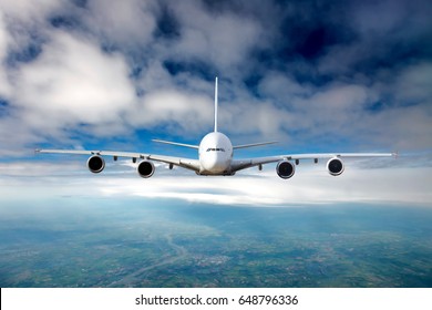 The passenger plane in flight. Aircraft flies high in the blue sky through the clouds. Airplane front view.