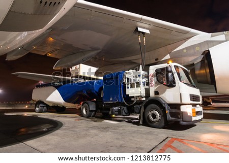 Passenger plane parked at the airport. Refueling operation in action. Fuel tanker vehicle. Kerosene. Handling and preparing for departure. Aircraft ground maintenance. Pre-flight service.