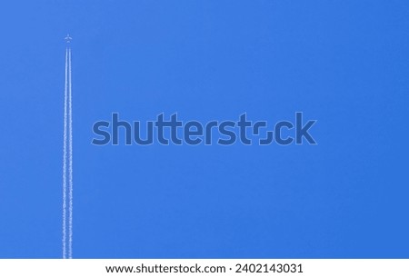 Passenger plane with reverse wake flies high in the blue sky. Trace of the plane in the sky