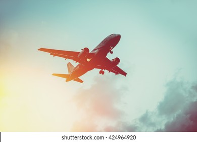 Passenger Plane In The Sky At Sunrise Or Sunset. Vacation And Travel Concept. Toned Image