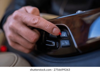 Passenger pressing button to move the front passenger seat forward to extend rear seat legroom in luxury car.