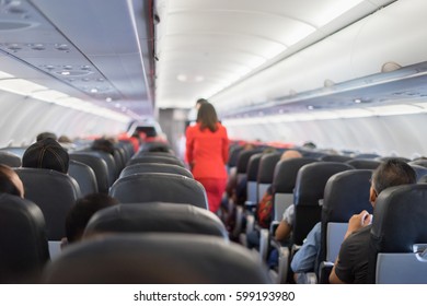 Passenger Seat, Interior Of Airplane With Passengers Sitting On Seats And Stewardess Walking The Aisle In Background. Travel Concept,vintage Color