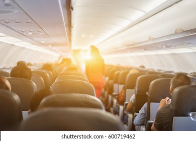 Passenger Seat, Interior Of Airplane With Passengers Sitting On Seats And Stewardess Walking The Aisle In Background. Travel Concept,vintage Color