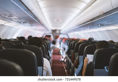 Passenger Seat, Interior Of Airplane With Passengers Sitting On Seats And Stewardess Walking The Aisle In Background. Travel Concept,vintage Color