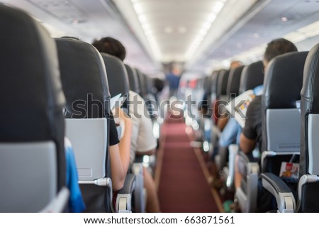 passenger seat, Interior of airplane with passengers sitting on seats and stewardess walking the aisle in background. Travel concept,vintage color Сток-фото © 
