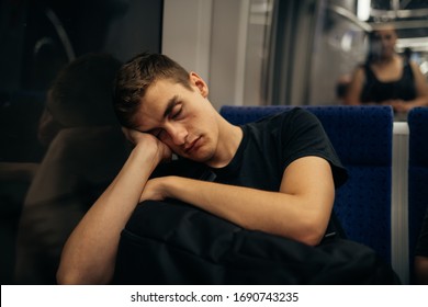 Passenger sitting in the seat and sleeping inside a train/bus while traveling.Tired exhausted looking young man getting away with train ride.Going home from work.Bored person during commute time.Nap