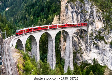 Passenger train crossing the Landwasser Viaduct in the Swiss Alps - Shutterstock ID 1950458716