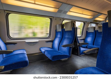 Passenger train with empty seats. Wide-angle long exposure, blurry green background out the window of an empty train in Switzerland, Europe, no people - Shutterstock ID 2300031257