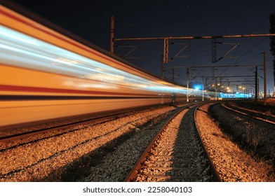Passenger train passing through the station at night. - Shutterstock ID 2258040103