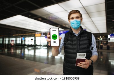 Passenger Travel For Work. Man Wearing Mask Hand Holding Mobile COVID-19 App For Test Results Before Airplane. Covid Pass For Traveling.  Phone In Airport Terminal In Background. PCR Test For Flight