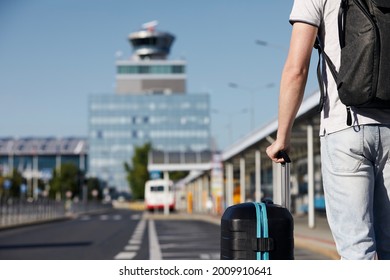 Passenger walking from bus station to airport terminal. Selective focus on hand holding suitcace. - Powered by Shutterstock