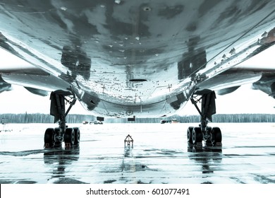 Passenger wide-body aircraft is parked on the airport apron. Airplane fuselage and main landing gear. Monochrome bottom view close up. - Powered by Shutterstock