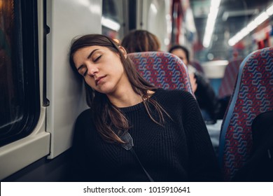 Passenger woman sitting in her seat and sleeping inside a train/bus while traveling.Tired exhausted woman taking a nap in public transportation.Falling asleep during a long ride. - Powered by Shutterstock