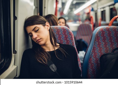 Passenger woman sitting in her seat and sleeping inside a train/bus while traveling.Tired exhausted woman taking a nap in public transportation.Falling asleep during a long ride. - Powered by Shutterstock