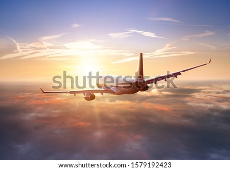 Passengers commercial airplane flying above clouds in sunset light. Concept of fast travel, holidays and business.