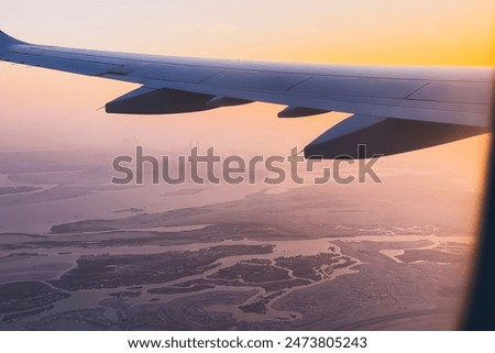 Passengers point of view window panorama of Abu Dhabi skyline and city with rivers and deserted landscape on sunset. Fly with low budget airlines holidays in UAE concept