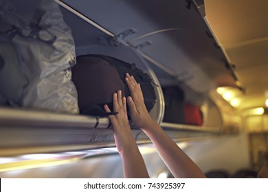 Passengers Putting Luggage Into Overhead Locker On Airplane. Hand Putting Luggage Into Panel Overhead Locker In Airplane.
