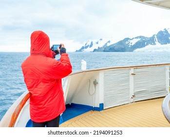 Passengers In Red Parkas On An Antarctic Expedition At The Bow Of A Ship	
