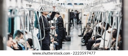 Passengers traveling by Tokyo metro. Business people commuting to work by public transport in rush hour. Shallow depth of field photo.