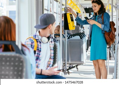 Passengers traveling in public transport. Handsome sad thioughtful man with a phone in his hands sitting next to a sitting red-haired girl riding in bus. Stranger on background View inside tram. - Shutterstock ID 1475467028