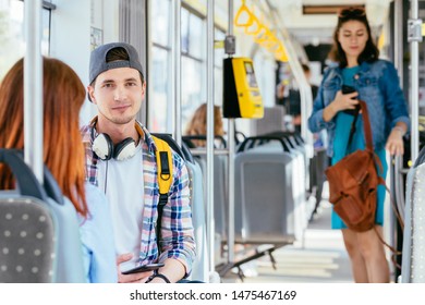 Passengers traveling in public transport. Handsome sad thioughtful man with a phone in hands sitting next to a sitting red-haired girl riding in bus. Beautiful stranger on background View inside tram. - Shutterstock ID 1475467169