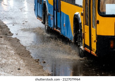 Passing Cars In A Large Puddle During Rain And Sleet. Large Splashes From Under The Wheels Of The Car. Mud, Snow And Puddles On A Major Highway In The City.