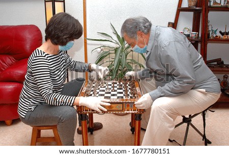 passing the time during the covid-19 quarantine, couple playing chess with masks and latex gloves, quarantined for covid-19, coronavirus,