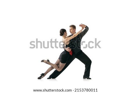 Passion, feelings. Dynamic portrait of flexible young dancers dancing Argentine tango isolated on white background. Artists in black stage costumes. Concept of art, beauty, grace, action, emotions.