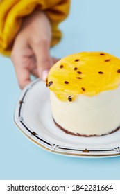 Passion Fruit Cheesecake On Light Blue Background Female Hand Grasping On Black And White Plate