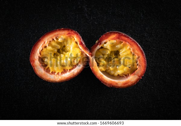 Passion\
fruit cut in half, arranged on a black\
background