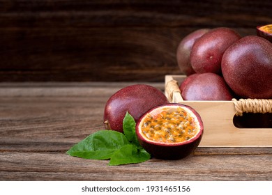 Passion Fruit ( Maracuya ) In Wooden Box And Cut In Half Slice With Green Leaves Isolated On Wooden Table Background . 