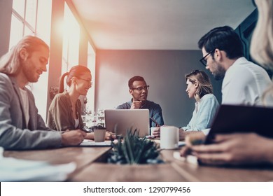 Passionate About Their Project. Group Of Young Modern People In Smart Casual Wear Discussing Business While Working In The Creative Office