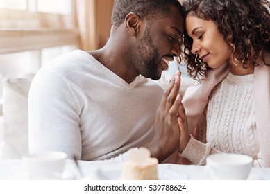 Passionate African American couple touching hands in the cafe