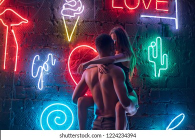 Passionate Couple Kissing On The Background Of Neon Lamps.