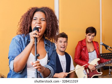 Passionate female singer performing with band members in recording studio - Powered by Shutterstock