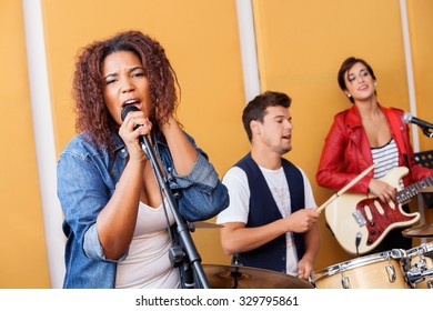 Passionate female singer performing with band in recording studio - Powered by Shutterstock