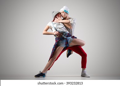 Passionate Hip Casual Couple Dancing. Two Modern Style Beautiful Performers Working Out. Performance Of Beautiful Pair Of Street Dancers. Boyfriend Holding Girlfriend. Studio Gray Background